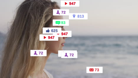 animation of social media icons on banners over relaxed caucasian woman admiring view by seaside