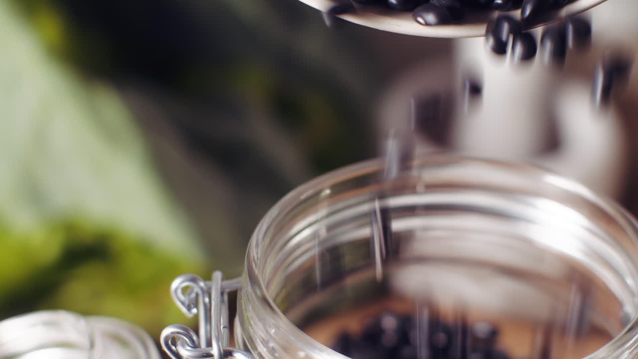 Black Beans being poured into a glass jar