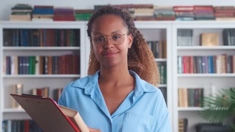 young intellectual african american woman tutor with books stands in library