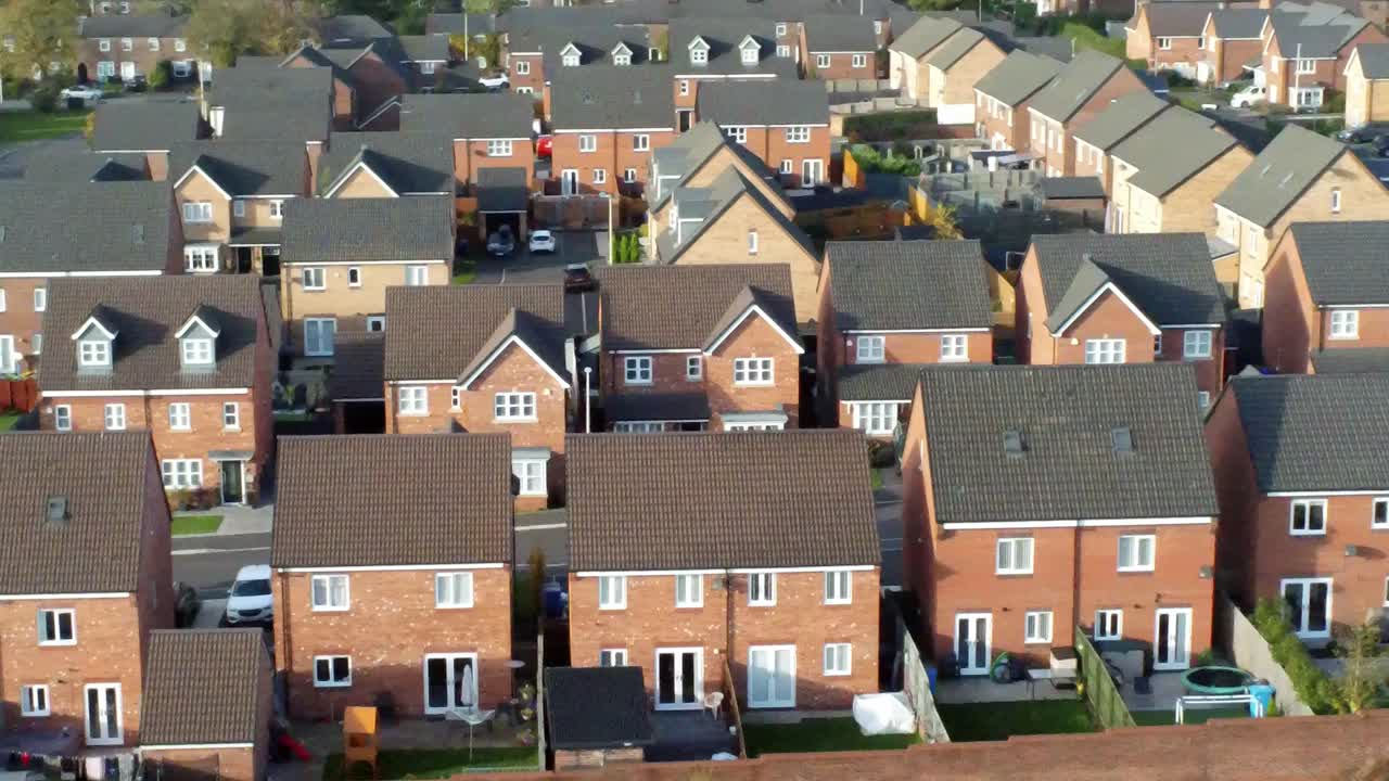 Property ladder new British housing estate aerial view overlooking rooftops slow dolly right shot