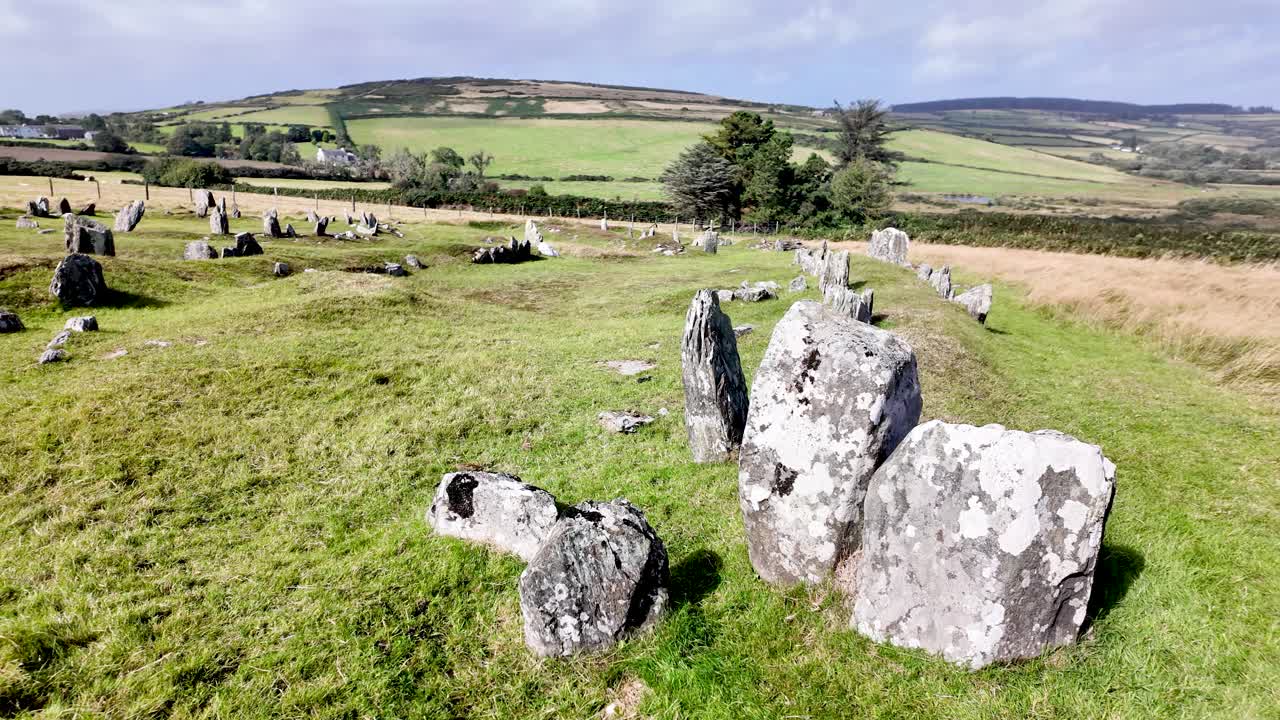 Open grassy field with standing stones and ancient round houses on Isle of Man, historic landscape