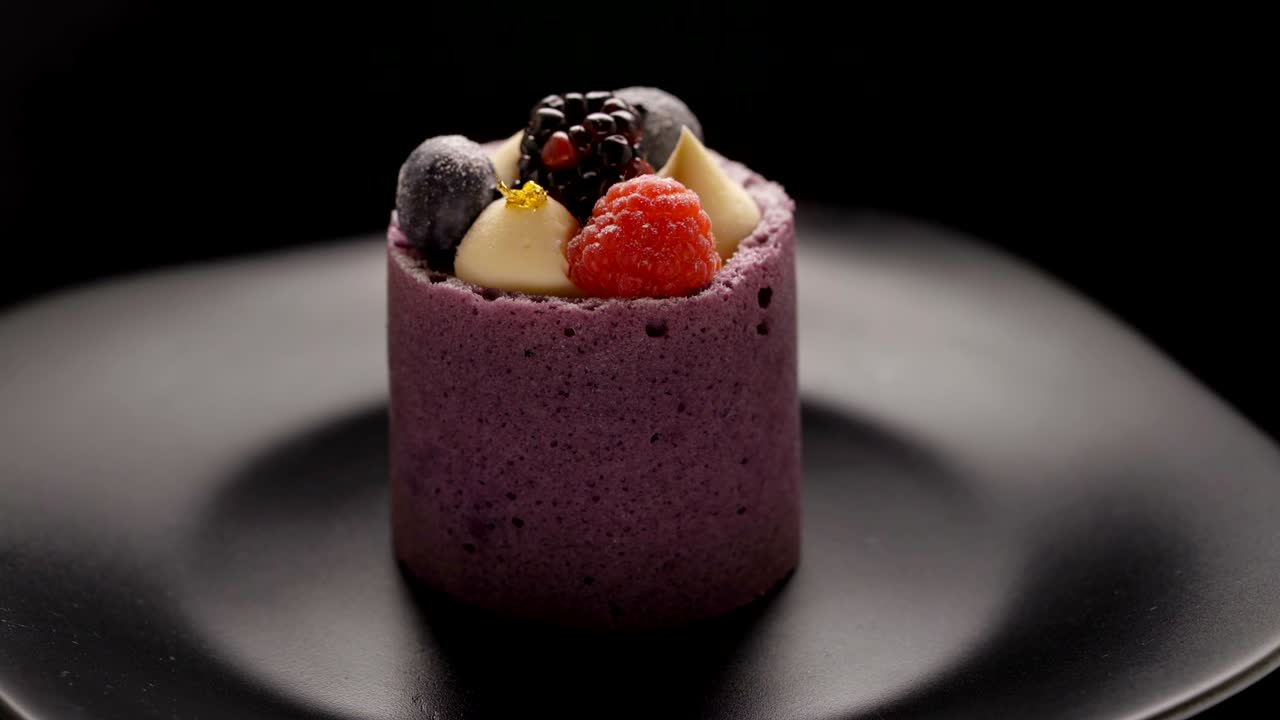 pasteles de mousse de bayas púrpuras con moras y frambuesas en un plato negro