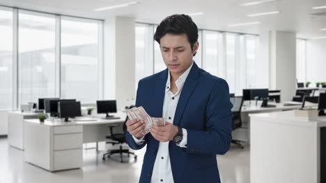 confused indian manager counting money in office