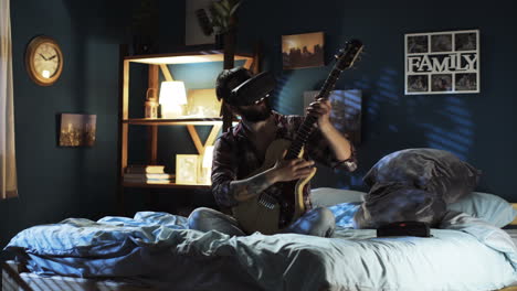 man playing guitar with vr headset in bedroom