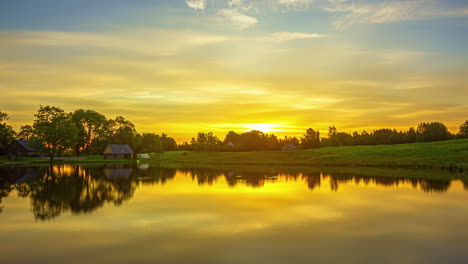 Cinematic-glowing-sunrise-over-lake-and-small-wooden-home,-time-lapse-view