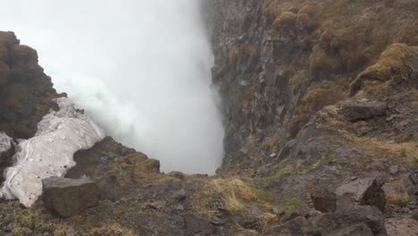 área geotérmica brumosa en islandia con aumento de vapor, terreno rocoso y restos de nieve