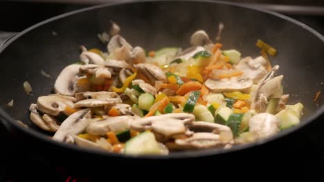 primer plano de la sartén de cebollas, zanahorias, champiñones y otras verduras finamente picadas fritas en aceite en una sartén