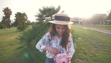 young woman taking a picture with a pink instant camera