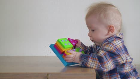 funny-boy-plays-with-bright-toy-leaning-on-low-table