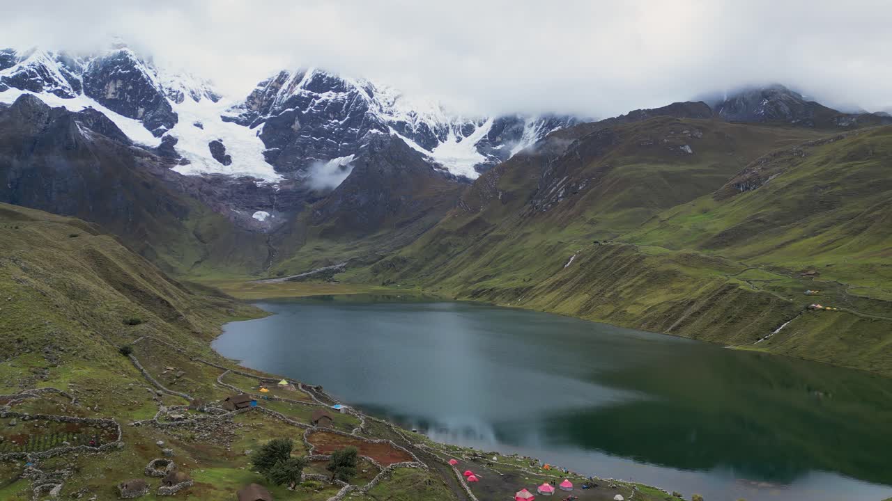 Flyover colourful tents at Laguna Carhuacocha in Peru mountain alpine