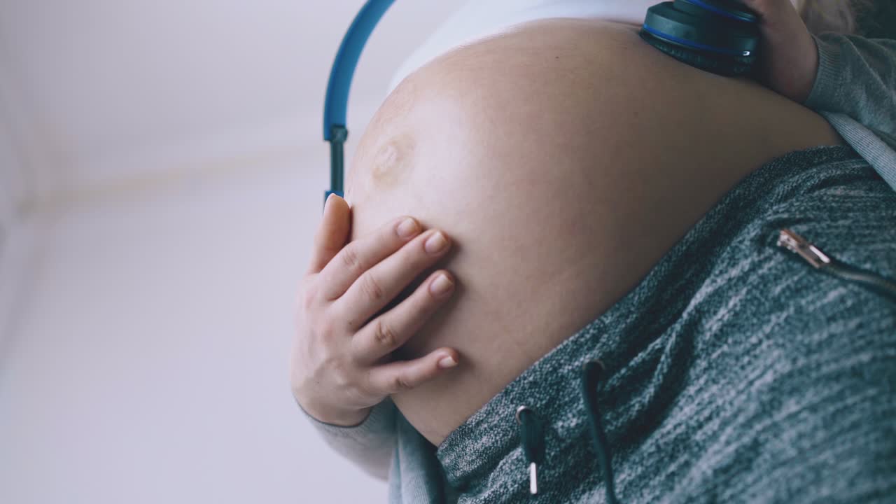 una bella donna incinta passa il tempo ad ascoltare musica con il bambino.