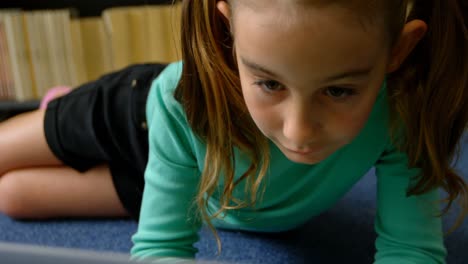 front view of attentive caucasian schoolgirl studying with laptop in library at school 4k