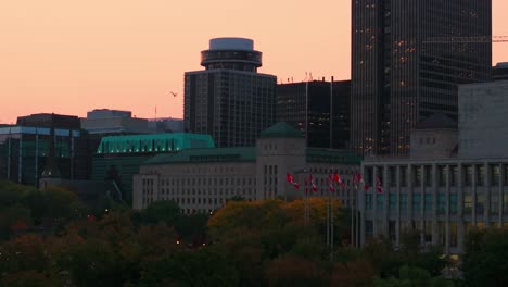 Early-morning-drone-shot-of-downtown-Ottawa,-showing-the-Canadian-library-and-national-archives-building-as-well-as-the-department-of-justice-with-Canadian-flags-flying