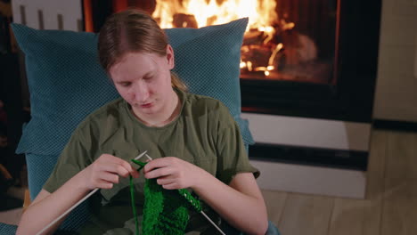 teenage girl knitting by the fireplace
