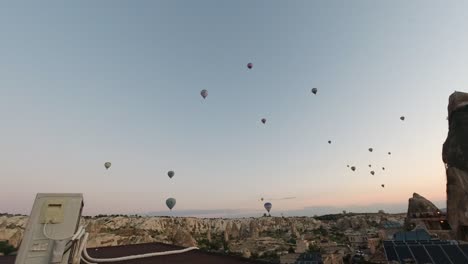 time-lapse of some hot-air balloons flying in the air in the middle of the natural rock structures and man-made accommodation in cappadocia, turkey