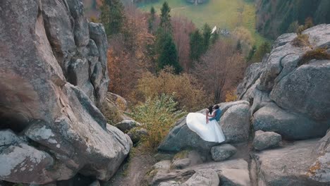 Newlyweds-stand-on-a-high-slope-of-the-mountain.-Groom-and-bride.-Arial-view