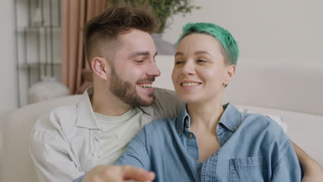 pareja feliz hablando y riendo juntos mientras están sentados en el suelo en casa