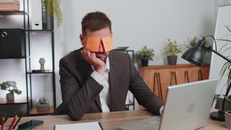 inefficient tired lazy businessman working sleeping on laptop computer with eyes stickers on face
