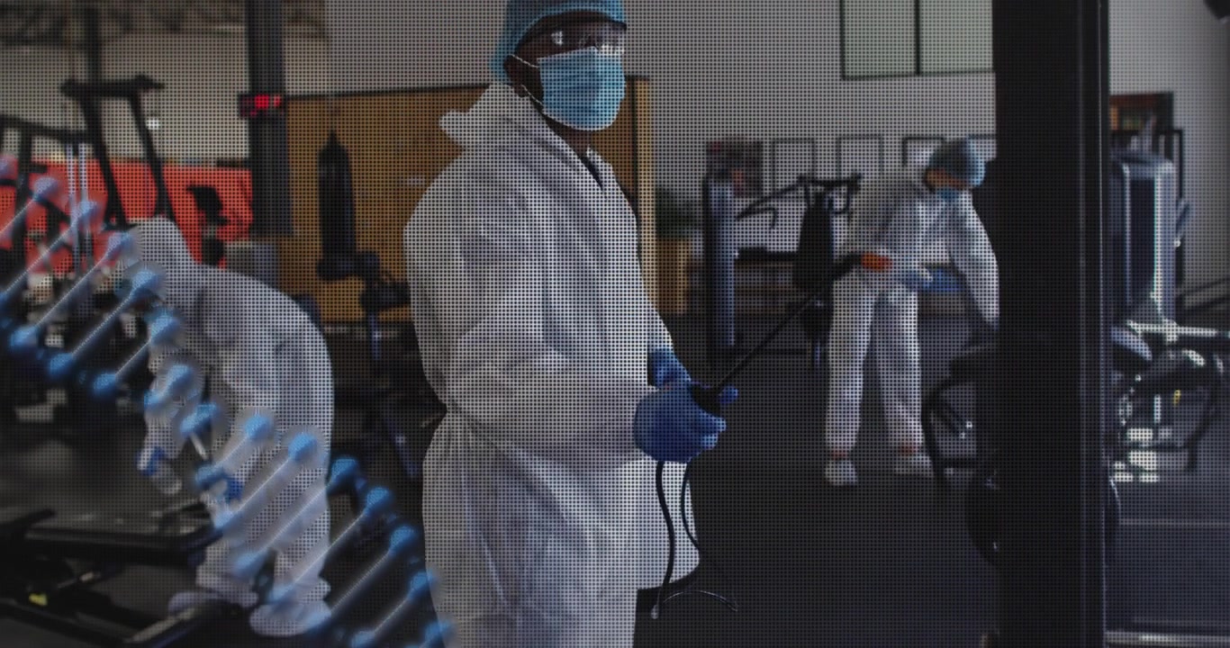Equipe de limpeza iniciando a pulverização programada de equipamentos de academia com um pulverizador, espiral azul marcando as zonas limpas.
