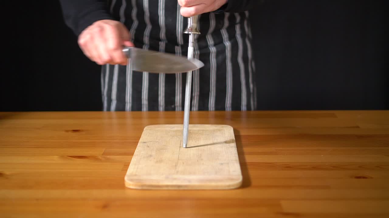 cámara lenta de un chef hombre usando varias técnicas para afilar un cuchillo con las manos, usando un cuchillo profesional y un acero afilado de diamantes