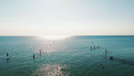 gente de pie paddleboarding en el océano