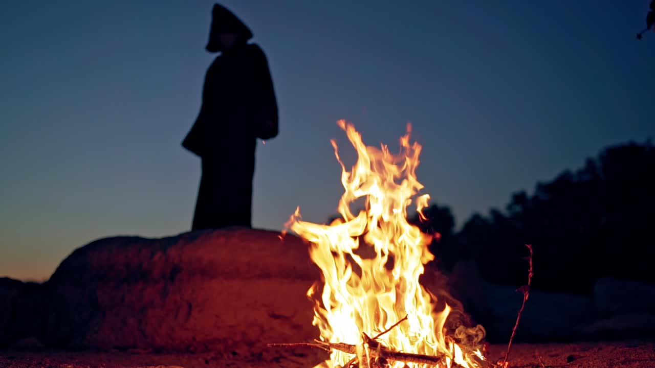 Old evil witch conjures in the wizarding lair. Scary Halloween concept. Burning fire.