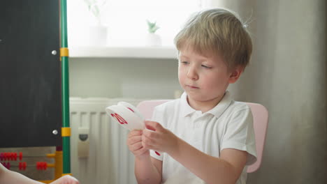 cute little boy learns cards with digits and fans at preschool