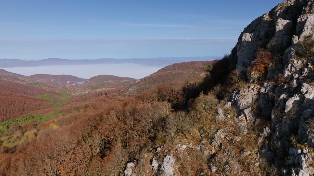 Autumn mountain landscape with forested hills and a foggy valley