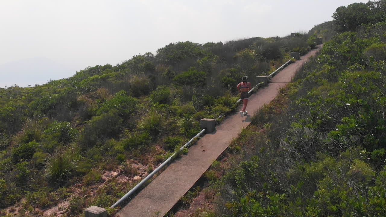 chica fitness corriendo por un sendero de montaña en una tarde soleada