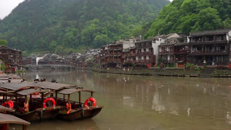 morning view of tuojiang river with boats and traditional houses in fenghuang, china