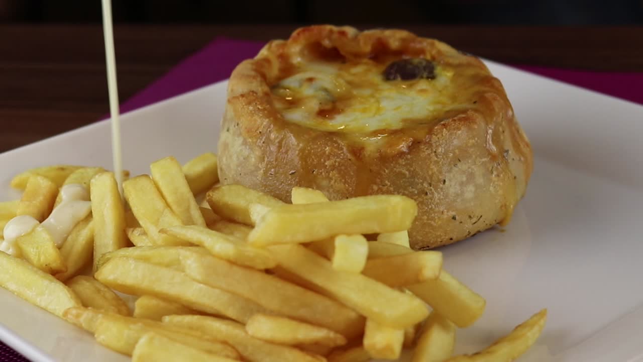 Creamy Sauce Poured Over Golden French Fries Next to a Savory Pie