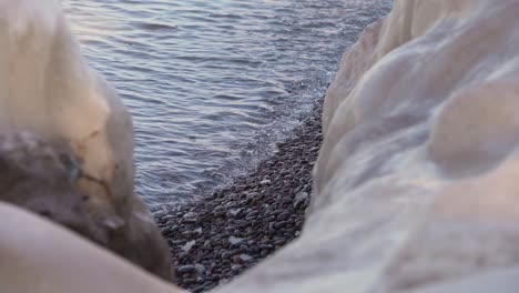 Cerca-Del-Agua-Del-Lago-Que-Fluye-A-Través-De-Guijarros-Mirando-Entre-Dos-Formaciones-De-Hielo-Derritiéndose