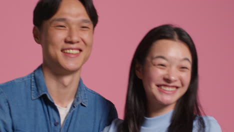 young loving couple in front of pink studio background having fun posing for photo booth style portraits 1