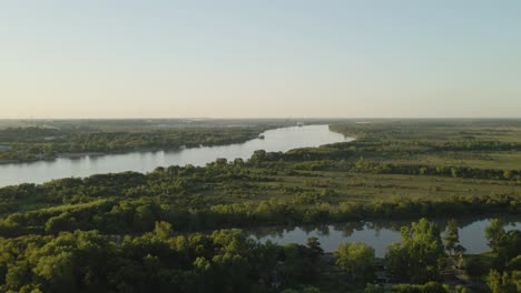 Paralaje-Aéreo-De-Zarate-Grandes-Campos-Verdes-Y-área-Forestal-Y-Río-Paraná-Que-Fluye-Hacia-El-Horizonte-A-La-Hora-Dorada,-Entre-Rios,-Argentina