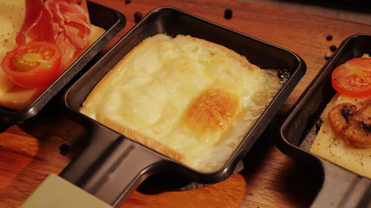 Traditional Swiss melted raclette cheese, hot melted French dish, family cooking dinner with Spanish style tapas ingredients and grill.