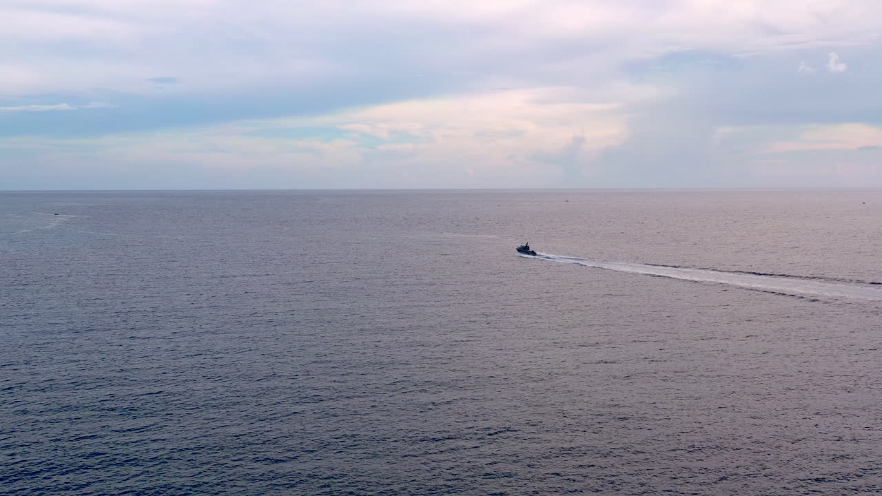 Aerial 4k shot of a motorboat sailing on a calm sea. Cloudy skies on the horizon.