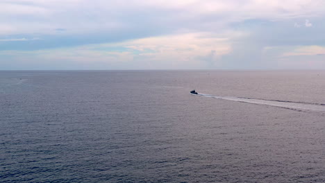 aerial 4k shot of a motorboat sailing on a calm sea. cloudy skies on the horizon.