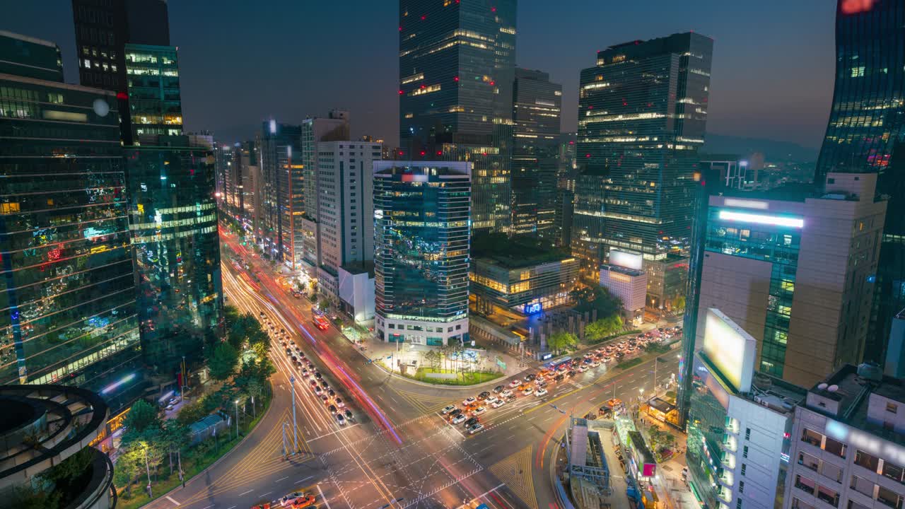 timelapse día a noche al atardecer de los senderos de luz la velocidad del tráfico a través de una intersección en el distrito comercial de gangnam center de seúl en la ciudad de seúl, corea del sur.