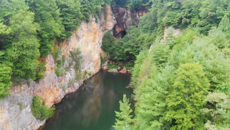 4k drone video of rock cliff next to burnett branch pond at emerald village near little switzerland, nc on summer day