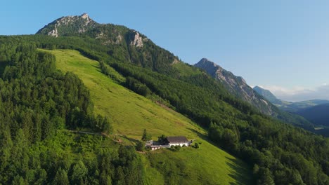 right-orbit drone circles laimeralm mountain inn perched high above lake wolfgangsee, bathing the alpine lodge and green hillsides in warm summer golden-hour light