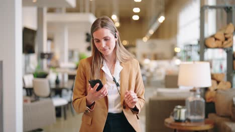 confident associate strolls between displays, smiling down at smartphone