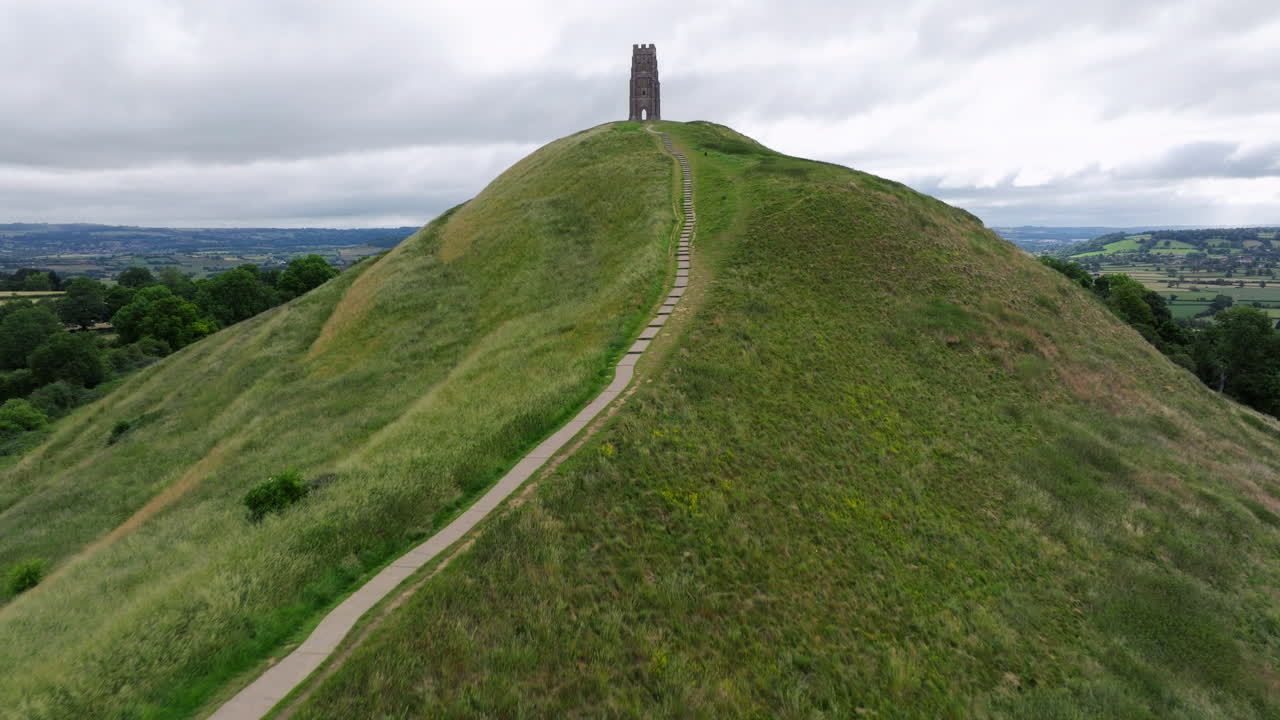 Path Leading Up To The Glastonbury Tor Mountain Peak In Glastonbury, Somerset, England. Aerial Drone Shot