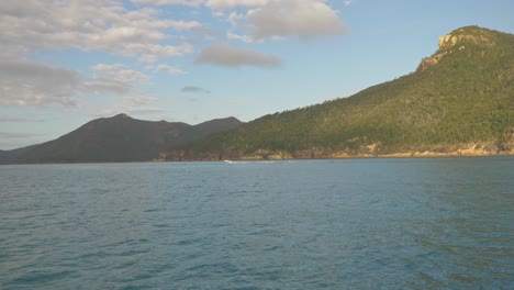 Distant-View-Of-A-Motorboat-Speeding-Across-Hook-Island-Passage-In-Whitsundays,-QLD-With-Rugged-Inlet-In-Background