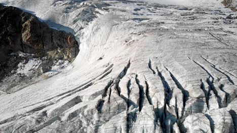 sobrevuelo aéreo sobre un glaciar cerca de arolla en valais, suiza con una vista panorámica desde las grietas en el hielo del glaciar hasta los picos de aiguilles rouges iluminados por el sol de la madrugada