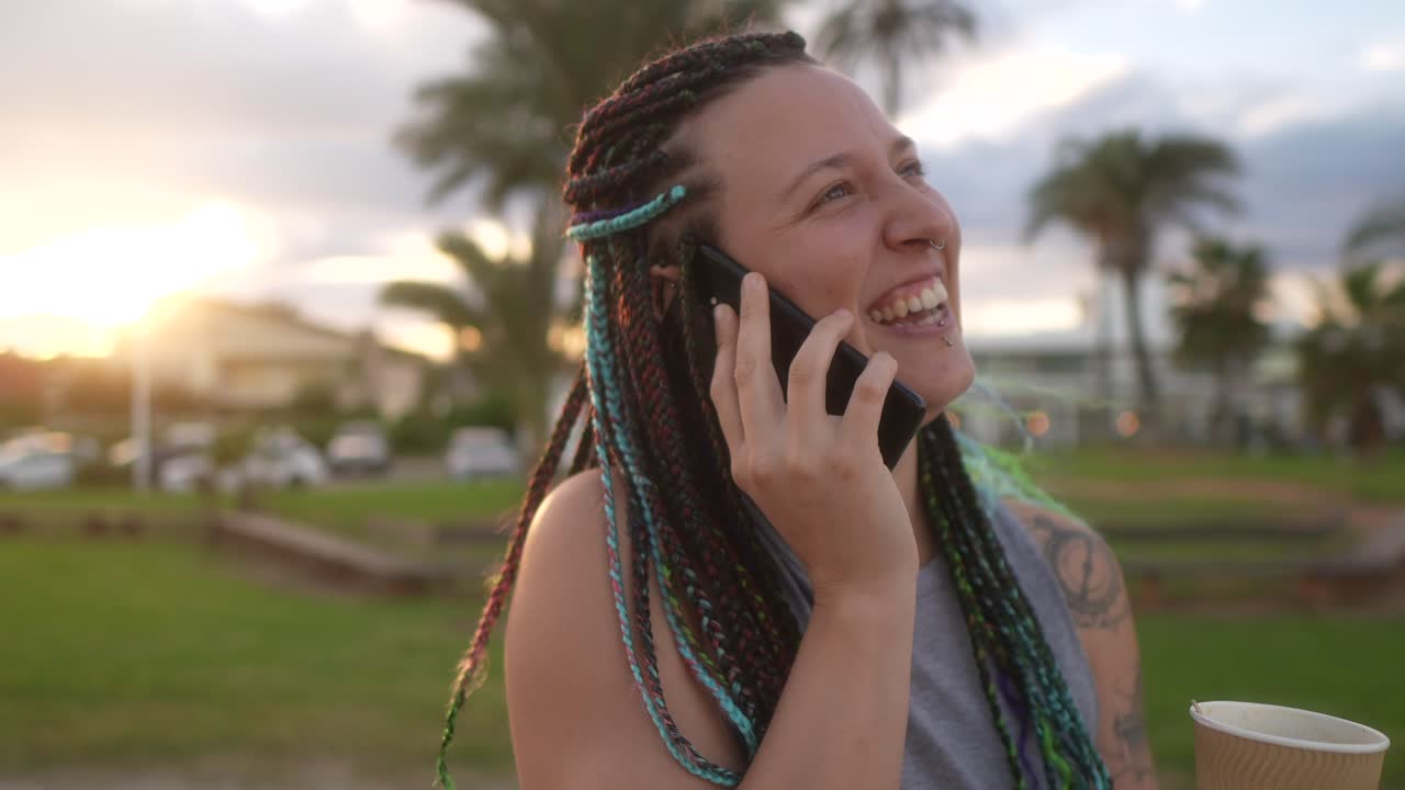 mujer con trenzas y sonrisa hablando en el teléfono inteligente