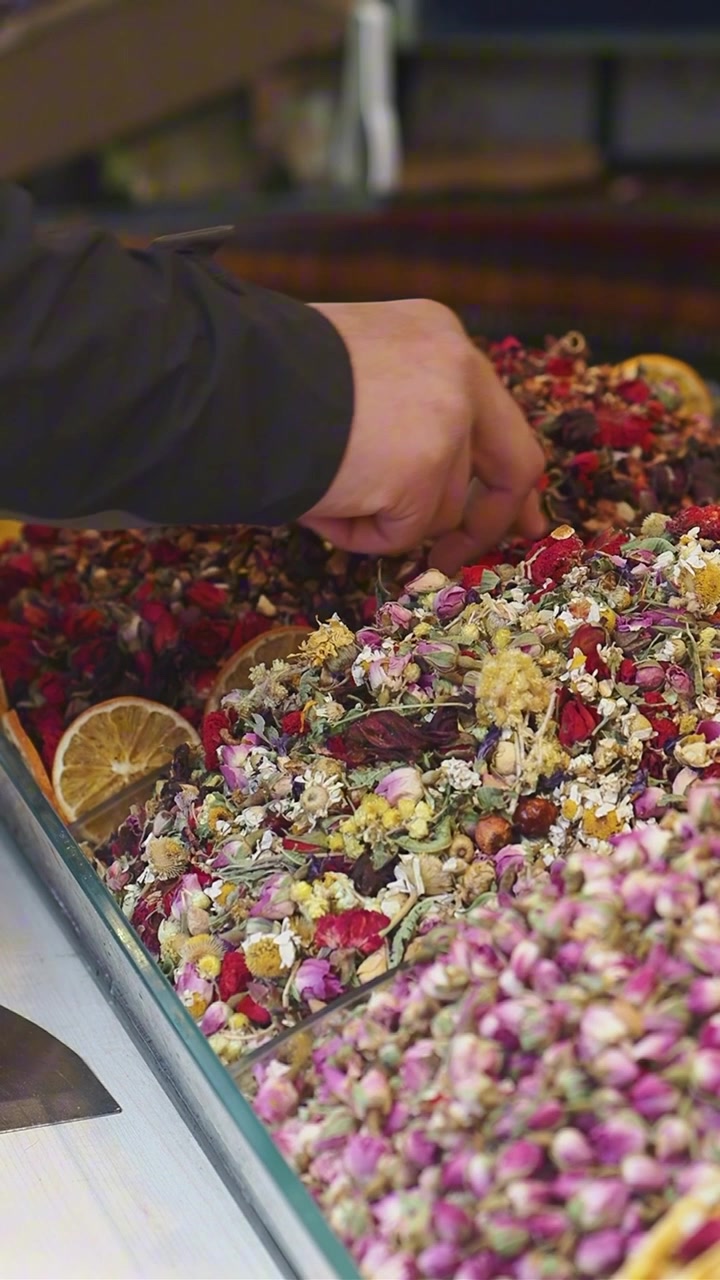 Hand Selecting Colorful Dried Flowers and Herbs for Tea at a Market