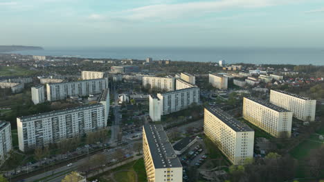 aerial view of apartment blocks in a city, with a glimpse of the sea in the distance, during late afternoon light