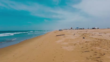 drone flies along beach as waves wash in shore