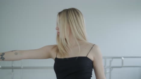 fit girl in black clothes performing contemporary. female dancer shows flowing motions, body and hands waves at white room. modern ballet dance choreography. young woman is moving smoothly