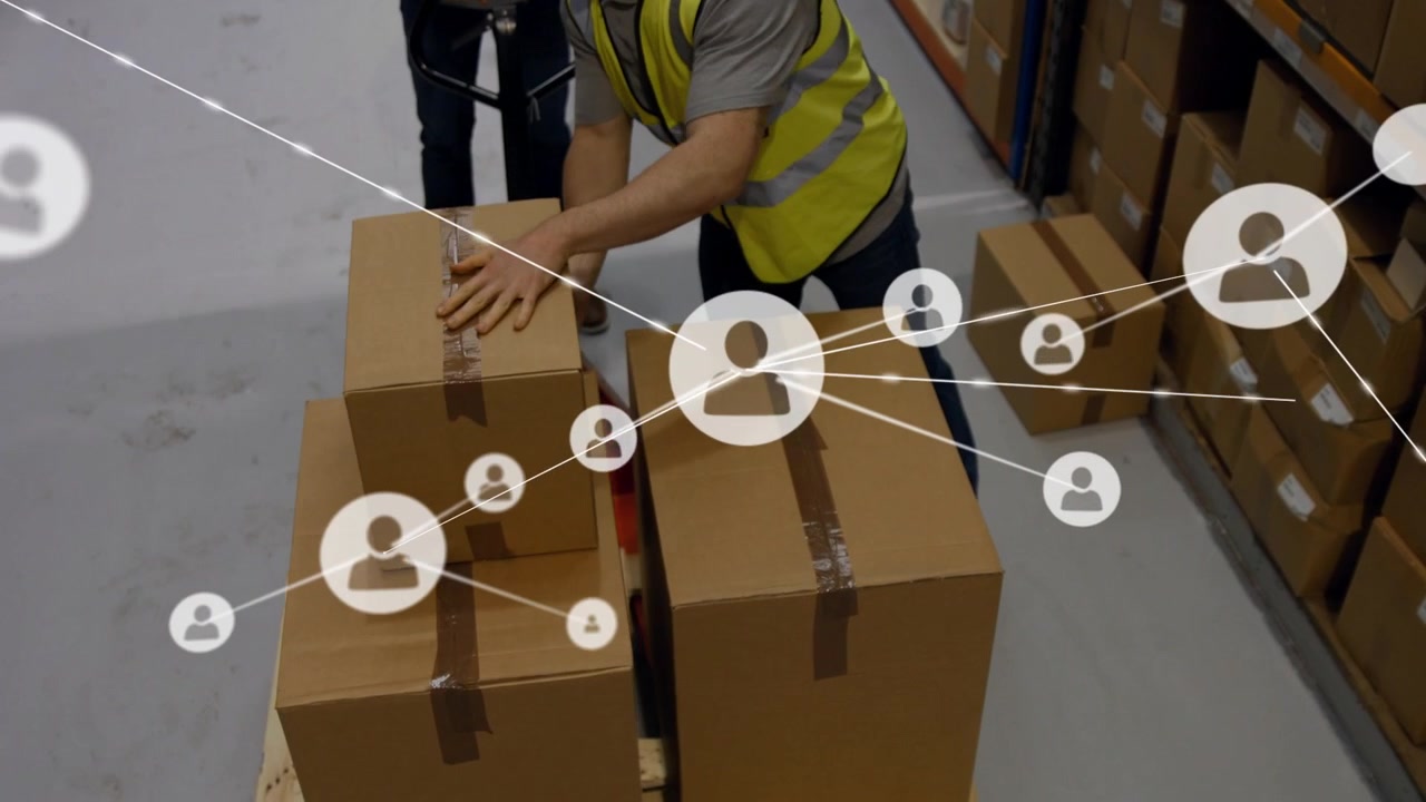 Personale del magazzino che impila scatole per la spedizione mentre un lavoratore inginocchiato solleva una scatola, con una sovrapposizione che copre il pallet.